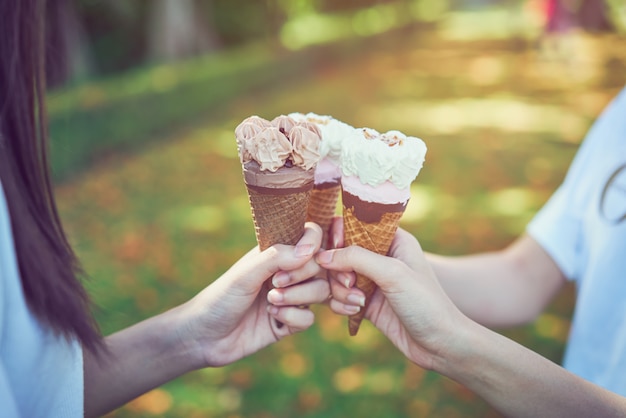 A mão das mulheres que guarda um gelado colide e feliz. o tempo de relaxamento.