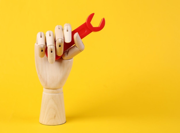 A mão de madeira guarda a chave dos brinquedos no fundo amarelo