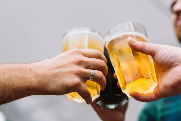 Foto a mão de um amigo a brindar um copo de cerveja.