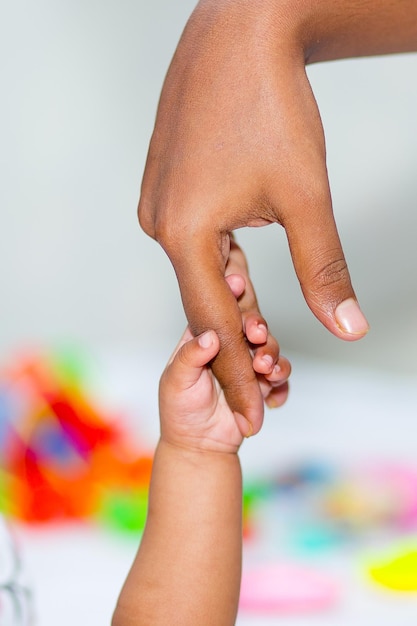 A mão de um bebê asiático segurando o dedo da mãe