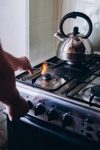 A mão de um homem com um fósforo acende um queimador de gás ou um fogão a gás na cozinha