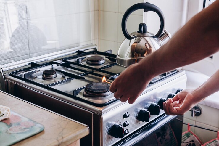 A mão de um homem com um fósforo acende um queimador de gás ou um fogão a gás na cozinha