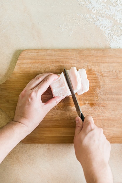 A mão de um homem corta os pedaços de gordura