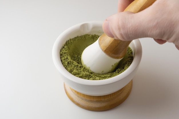 A mão de um homem mói chá matcha em um almofariz com um pilão Preparação de chá verde matcha japonês