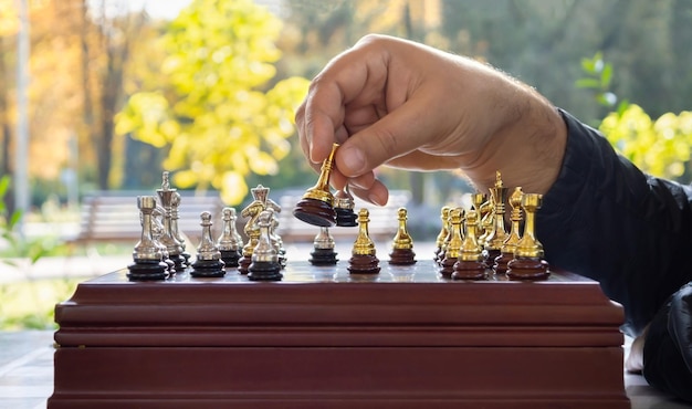 A mão de um homem remove a figura do oponente em um jogo de xadrez. xeque-mate. estratégia de sucesso. jogue xadrez ao ar livre.