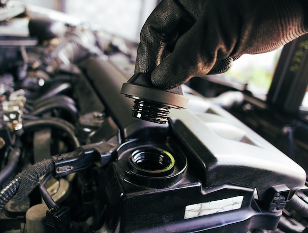 A mão de um mecânico de carro abre a tampa do óleo do motor para inspecionar antes de trocar o óleo do motor do carro Conceito de manutenção do carro