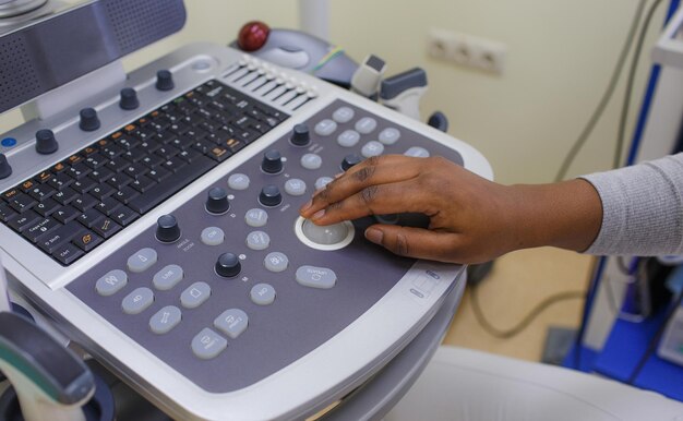 Foto a mão de um médico africano está no painel de controle de uma máquina de ultrassom