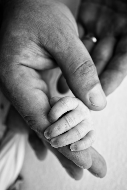 Foto a mão de um recém-nascido dormindo na mão dos pais mãe e pai closeup dedos minúsculos de um recém-nascido a família está de mãos dadas macrofotografia em preto e branco conceitos de família e amor