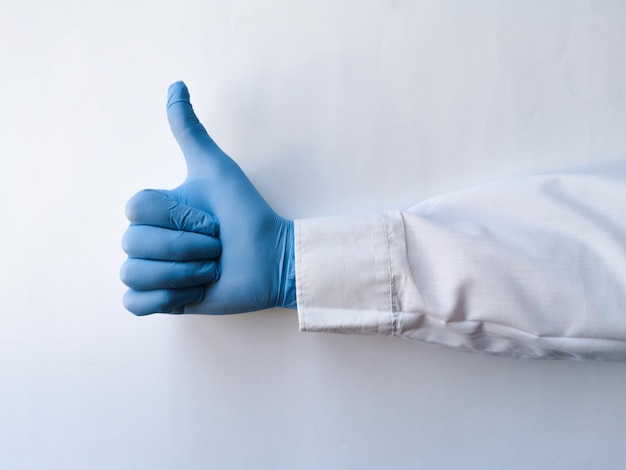 A mão de um trabalhador médico mostra o polegar no fundo isolado branco Gestos de mão