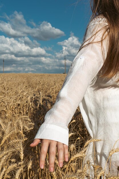 A mão de uma menina ucraniana toca as espigas de trigo com a mão no fundo de um campo Símbolo da liberdade ucraniana O conceito de alimento e pão de fertilidade