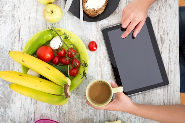 A mão de uma mulher com comida e tablet