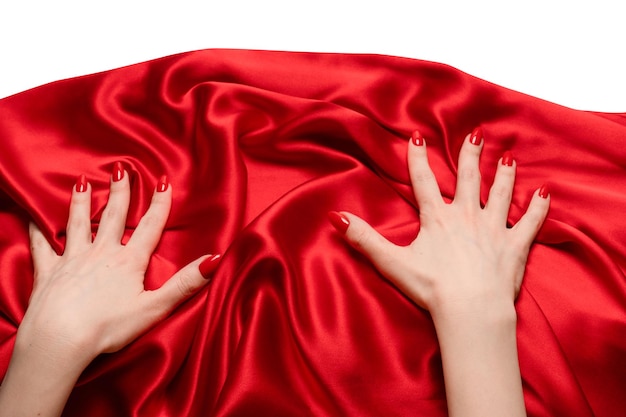 A mão de uma mulher com unhas vermelhas está tentando arrancar um tecido de seda vermelho