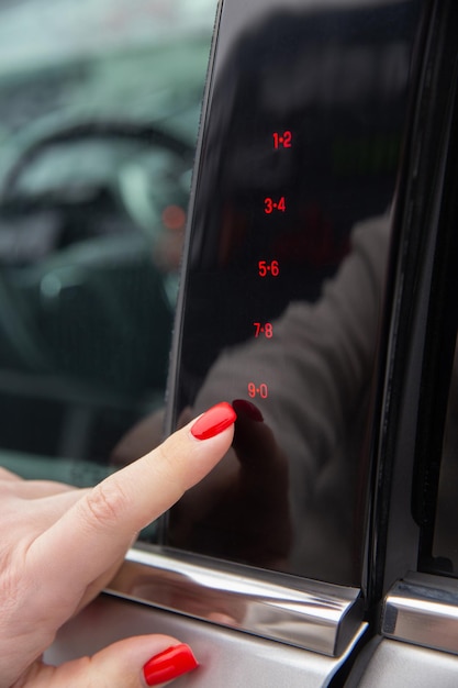 Foto a mão de uma mulher digita o código secreto para abrir a porta do carro no painel de toque