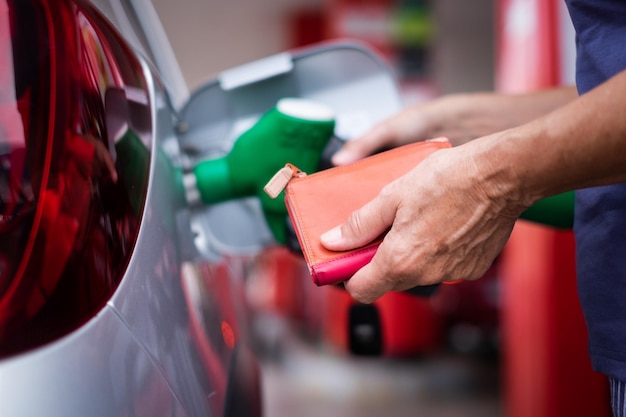 Foto a mão de uma mulher enchendo o tanque do carro na estação de serviço da bomba para o conceito de transporte de energia aumentando a inflação dos preços