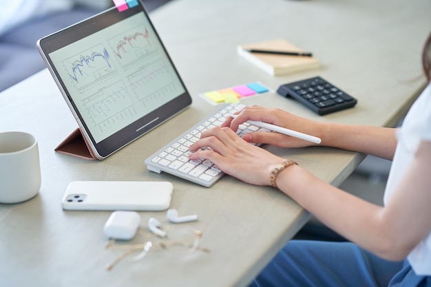 A mão de uma mulher operando um tablet PC na sala