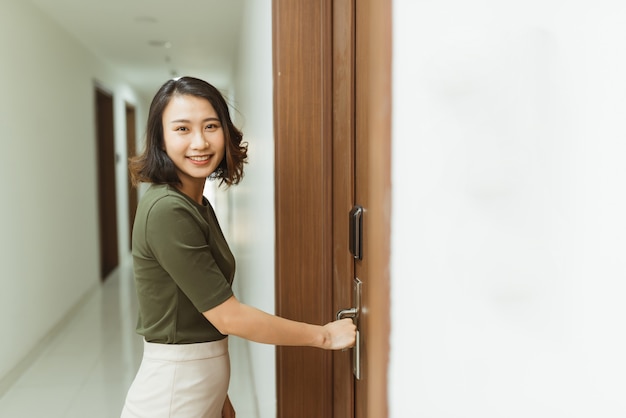 A mão de uma mulher segurando uma fechadura eletrônica moderna abre a porta do apartamento