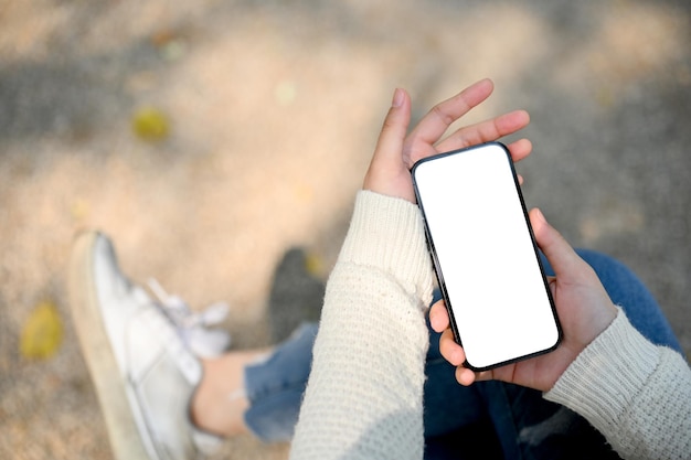 A mão de uma mulher segurando uma maquete de smartphone sobre a rua desfocada ao fundo