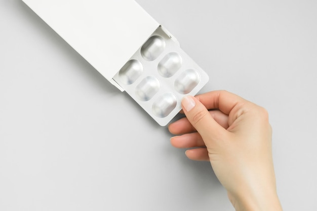 a mão de uma mulher tira uma bolha com comprimidos da embalagem tomando o conceito de tratamento de comprimidos