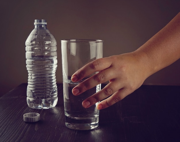 A mão de uma mulher toma um copo de água