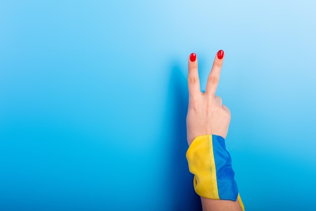 A mão de uma mulher ucraniana com bandeira na mão na cor amarela azul o fundo azul da paz