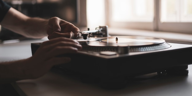 A mão de uma pessoa próxima colocou a agulha em um disco, tocando um disco de vinil na festa