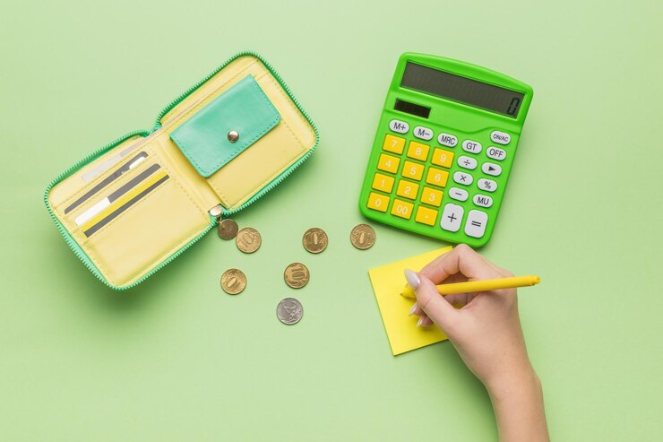 Foto a mão de uma rapariga com uma caneta uma calculadora e uma carteira sobre um fundo verde o conceito de gestão orçamental flat lay