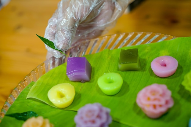 A mão do chef tailandês está decorando Variedades tradicionais coloridas sobremesas tailandesas conjunto de farinha fumegante creme preto creme de coco creme fumegante de camada de feijão bolo pudim