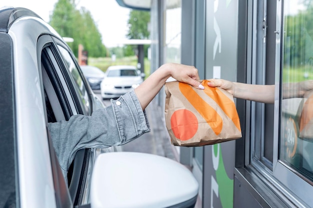 A mão do cliente pega um pacote de comida da máquina do análogo russo do McDonald's Vkusno e tochka 20230723 Moscou Rússia