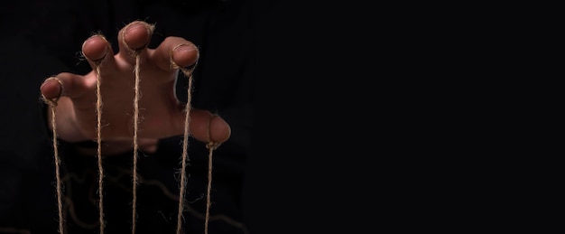 A mão do conceito de manipulação do abusador manipula no banner de fundo preto com espaço de cópia