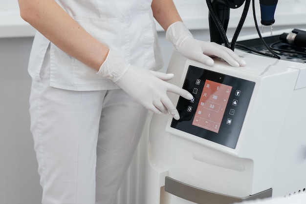 Foto a mão do cosmetologista ajusta um laser moderno em um close de salão de beleza pulsos de laser limpam a pele cosmetologia de hardware o processo de fototermólise aquecendo a pele