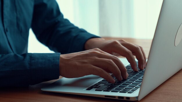 A mão do empresário trabalha em um laptop capaz na mesa do escritório, tiro de perto