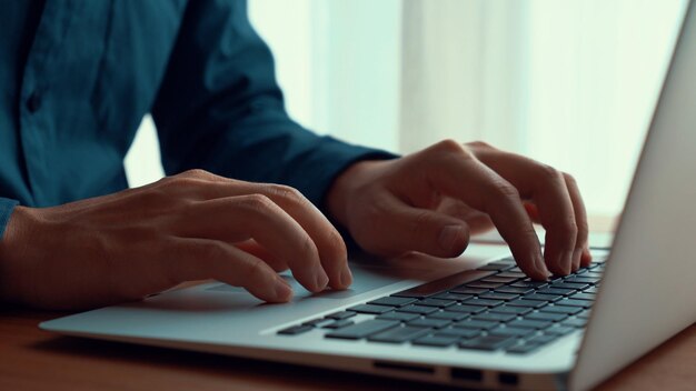 A mão do empresário trabalha em um laptop capaz na mesa do escritório, tiro de perto