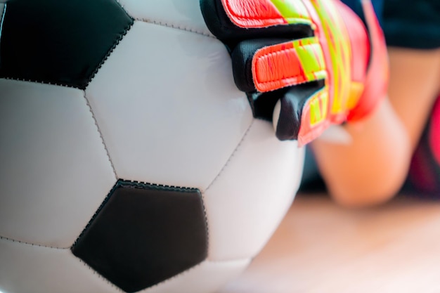 A mão do goleiro de futebol infantil está pegando um tiro de futebol fechado