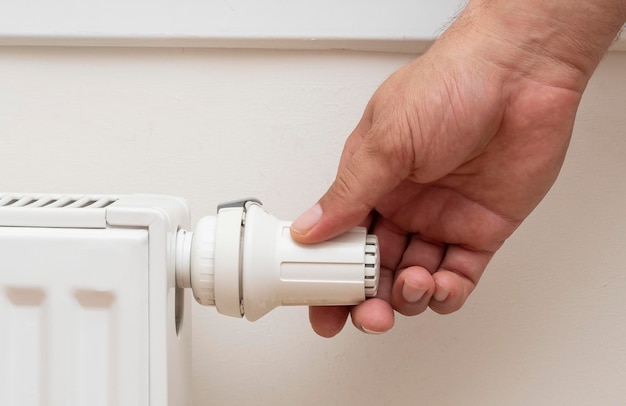 A mão do homem ajustando a temperatura de um radiador Adequado para notícias de caminhada de gás natural