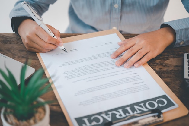 A mão do homem de negócios está assinando um contrato no acordo