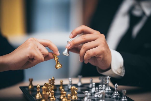 A mão do homem de negócios que move a figura da xadrez no jogo do sucesso da competição. conceito de estratégia, gestão ou liderança