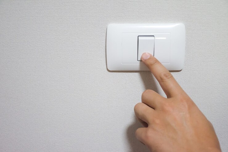 A mão do homem está ligando ou desligando o interruptor da luz elétrica