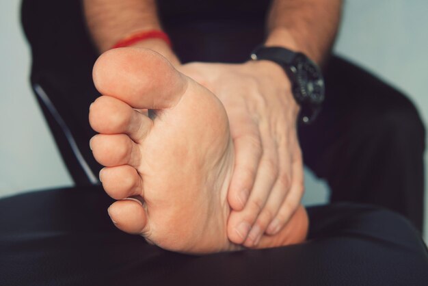 Foto a mão do homem sendo massageada em um homem com gota dolorosa e inflamada no pé ao redor do dedão do pé