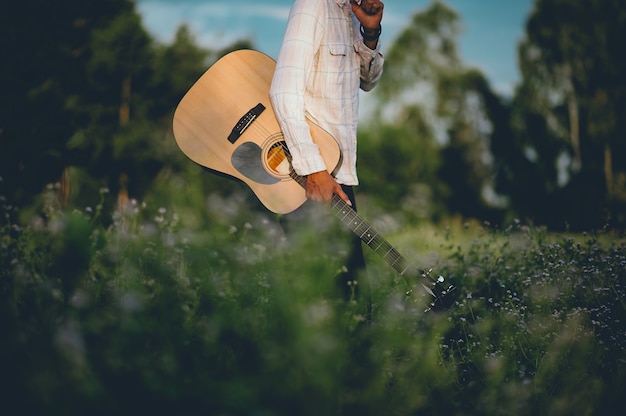 Foto a mão do homem toca violão, toca violão no jardim sozinho