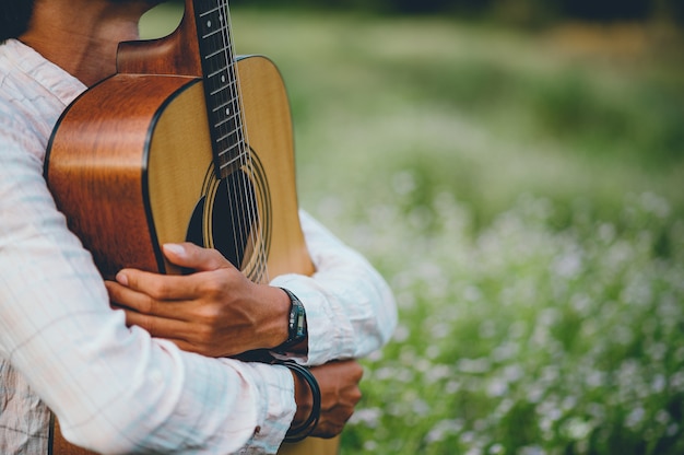 A mão do homem toca violão, toca violão no jardim sozinho