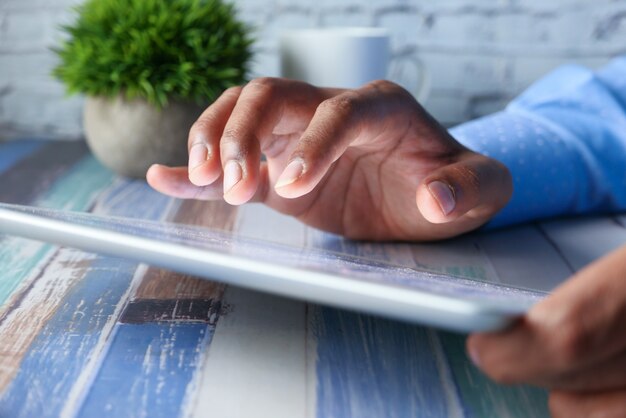 Foto a mão do homem trabalhando em tablet digital na mesa de escritório,