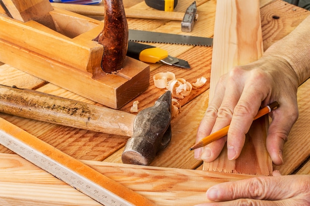 A mão do homem trabalhando na mesa de carpinteiro e ferramentas de trabalho
