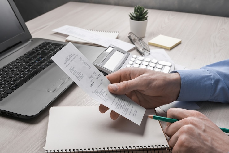 Foto a mão do homem usando a calculadora e a escrita toma nota com calcular sobre o custo e os impostos no escritório doméstico. empresário cuidando da papelada no local de trabalho