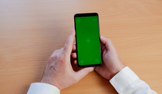 A mão do homem usando smartphone móvel com tela verde.