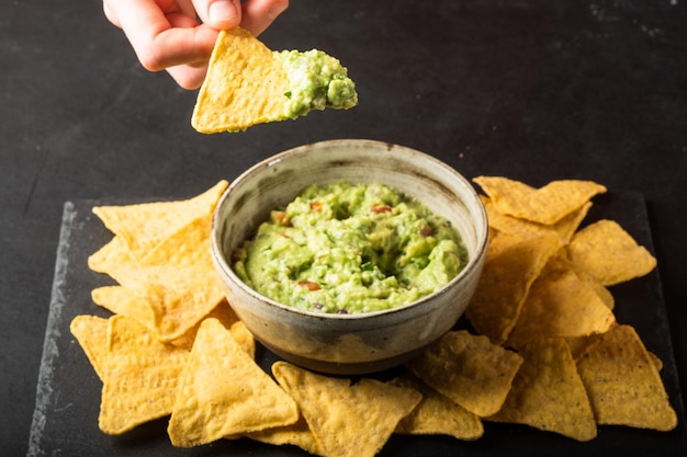 A mão do jovem está escolhendo um mergulho de guacamole com nachos Comida Vegetal Vegetal Saudável