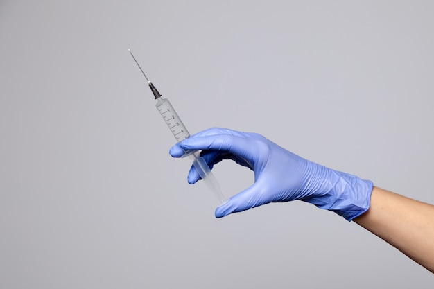 Foto a mão do médico closeup na luva de borracha de látex roxa segurar a seringa transparente