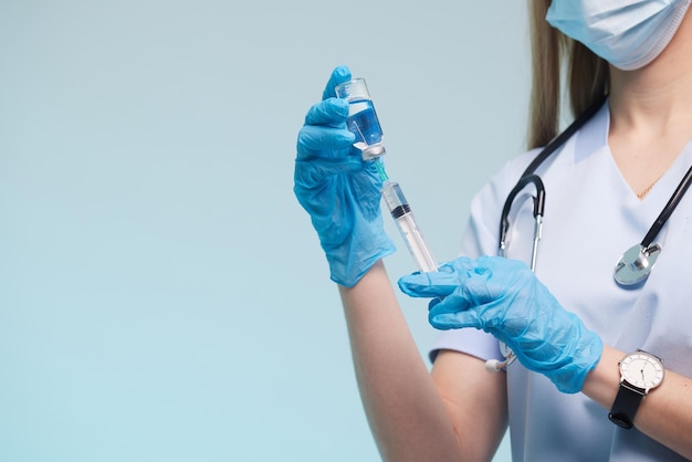 A mão do médico usa uma luva médica segurando uma seringa enquanto toma uma vacina líquida