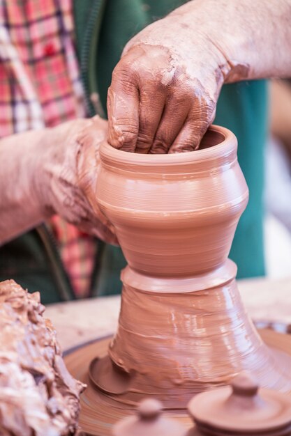 A mão do oleiro molda um vaso.