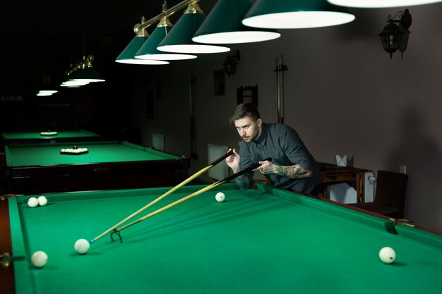 Mão do homem jogando sinuca no bar com bola de snooker