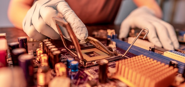 A mão enluvada do engenheiro está segurando o chip da CPU no fundo da microeletrônica de hardware de alta tecnologia da placa-mãe